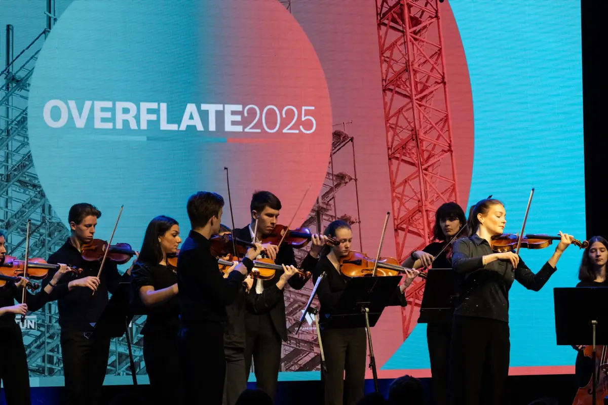 Unge strykere spiller på scenen foran skjerm med teksten «Overflate 2025»